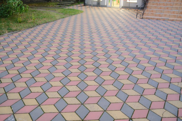 Multi-colored blocks form a patterned driveway leading to a building