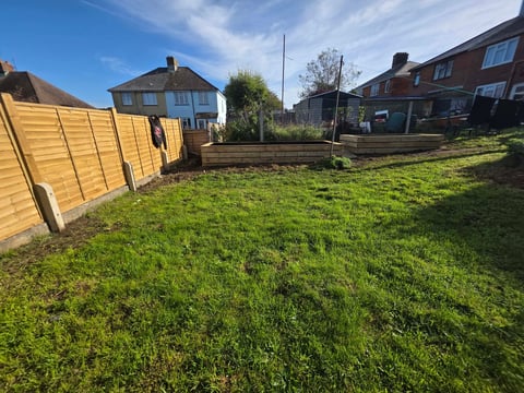 Residential backyard with wooden fence, green lawn and brick houses
