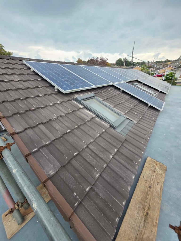 Solar panels installed on a residential roof with gray tiles, overlooking a suburban neighborhood with houses and green trees