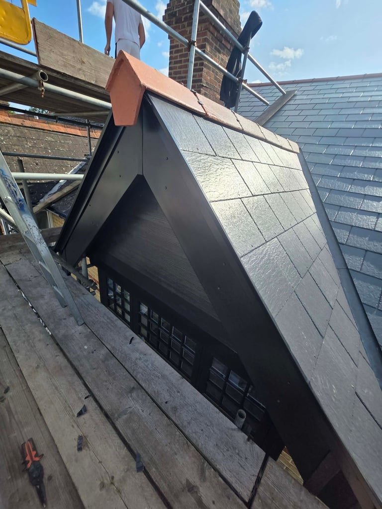 Modern black residential roof addition with copper flashing being installed on existing tiled roof structure