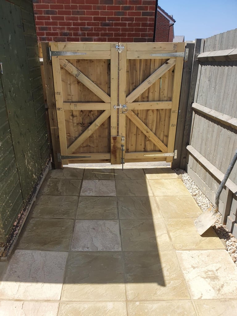 Wooden driveway gates with X-pattern design in fenced courtyard